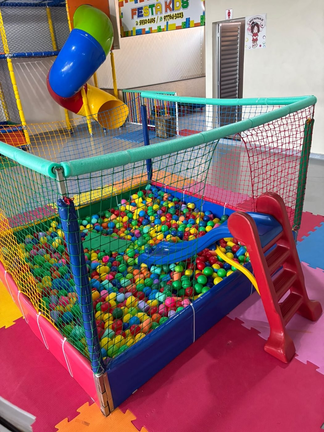 Piscina de bolinhas colorida com rede de proteção e escorregador