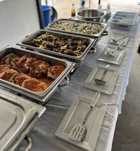 Réchauds em inox com alimentos servidos em mesa de buffet